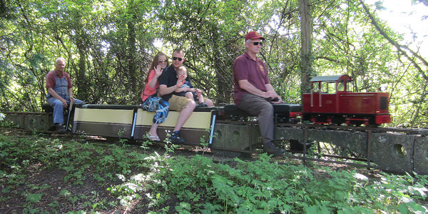 Passengers wave as the train passses the miniature railway